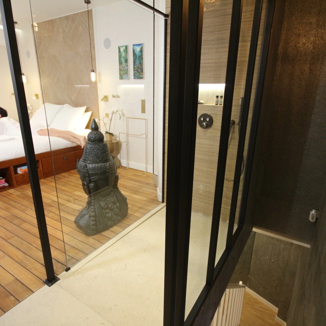 Vista del dormitorio y su cerramiento de cristal, con una persona tumbada en la cama.