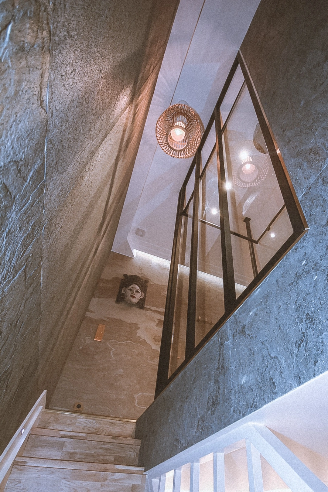 Escalier du duplex bordé de feuilles de pierre naturelle et d’une verrière