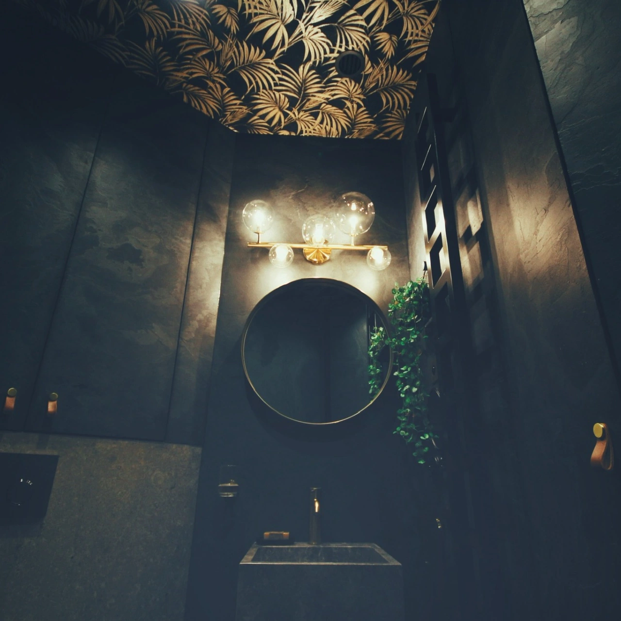 Round mirror, wall lights and a ceiling with botanical patterns
