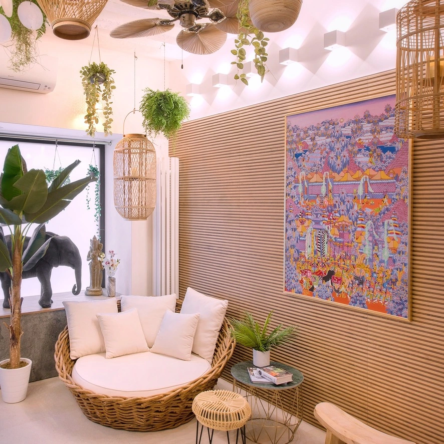 Un sillón de ratán, un cuadro balinés y vegetación en el salón del dúplex.