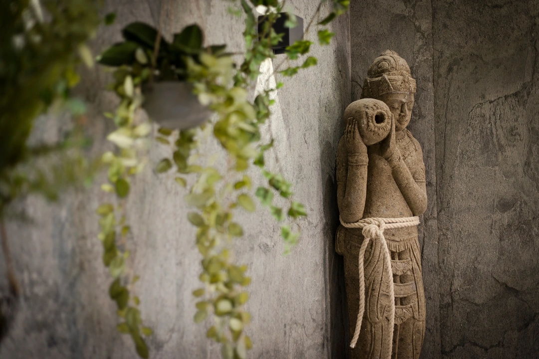 Grande sculpture balinaise contre le mur en pierre naturelle