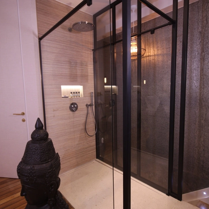 La mampara de cristal de la ducha en la planta superior, junto a una escultura balinesa.
